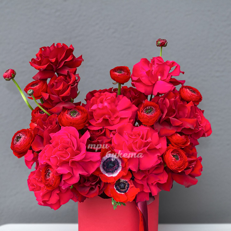 Красные розы, ранункулюсы и анемоны в коробке (крупный план)